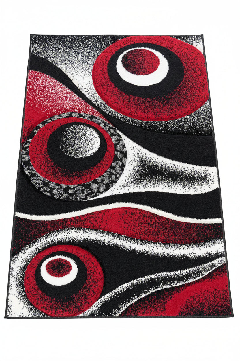 Abstract rug with red, black, and white circular patterns on a textured surface.