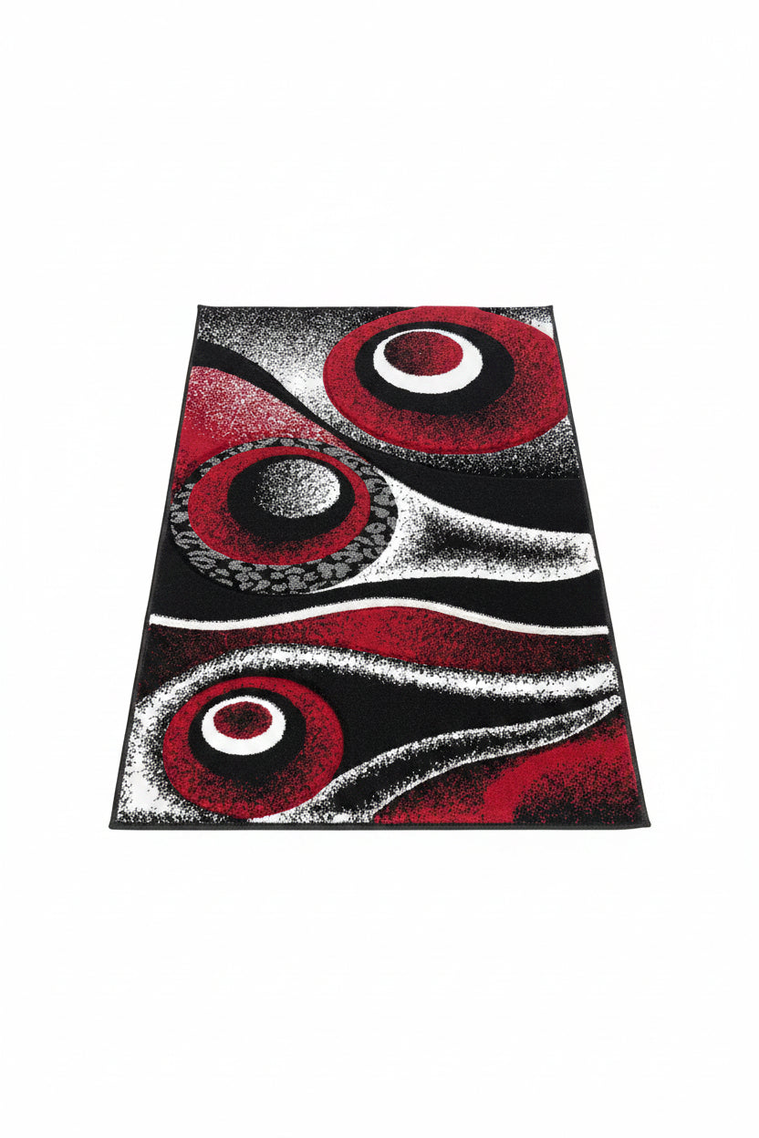 Decorative rug with red, black, and white circular patterns on a textured surface.